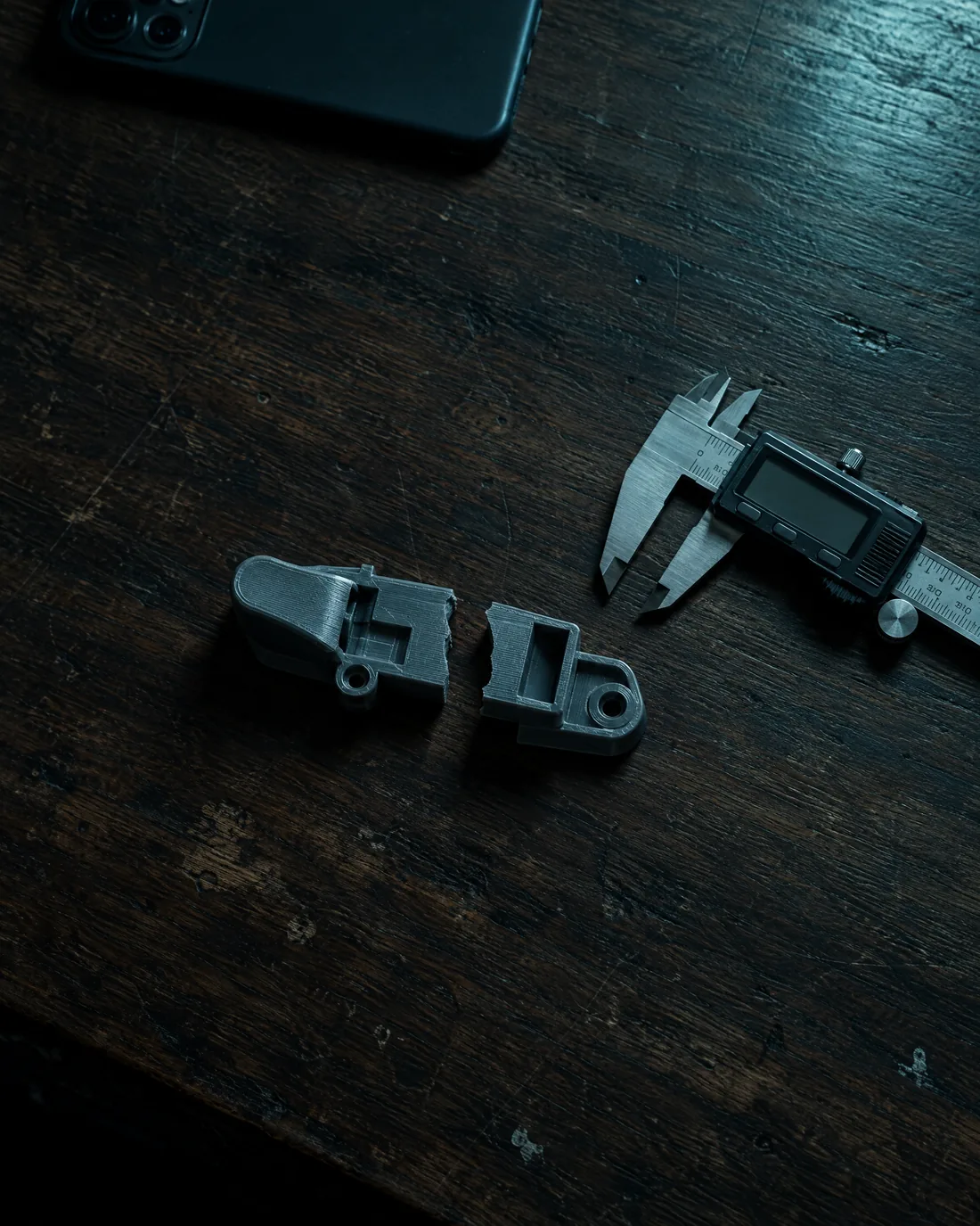 A grey plastic latch snapped in two, next to a pair of digital calipers